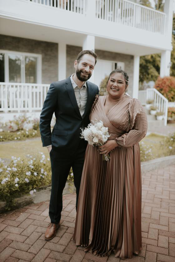 A Filipina and her partner smiling together outside a home